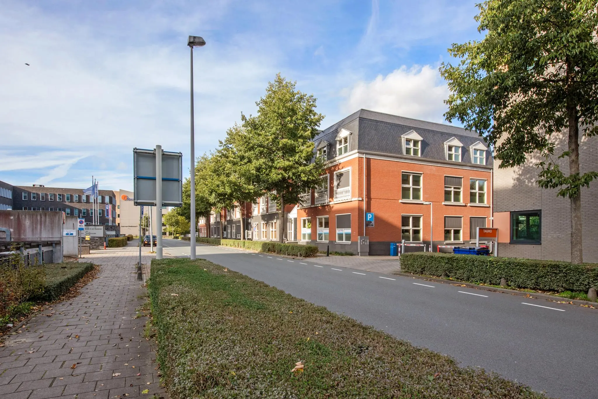 Straatbeeld van de Laan van Vredenoord met moderne kantoorgebouwen en een rood bakstenen pand aan de rechterzijde.